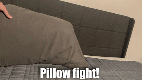 a person holding a pillow on a bed with the words pillow fight