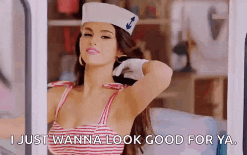 a woman in a sailor hat is standing in front of a window and says `` i just wanna look good for ya '' .