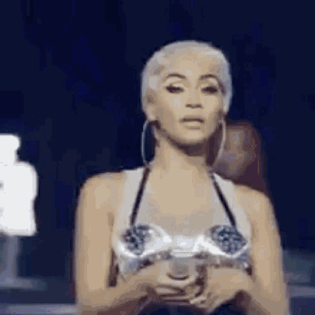 a woman in a bra is standing on a stage holding a trophy .