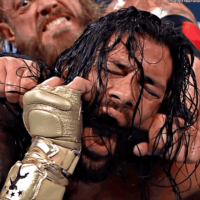 a wrestler wearing a gold glove with the letters e on it