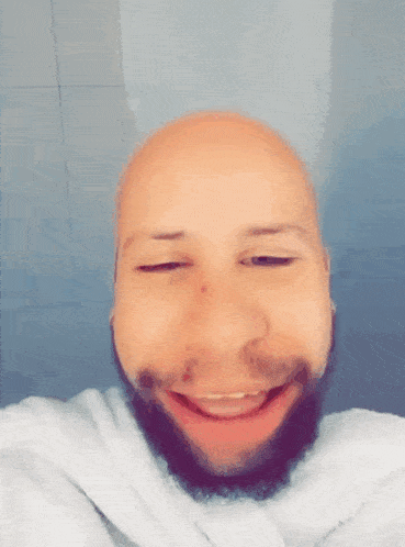 a bald man with a beard is smiling and making a funny face
