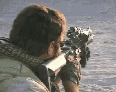 a man with a beard is holding a rifle in the desert