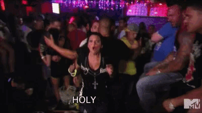 a woman is making a funny face in a crowd at a party and says holy shit !
