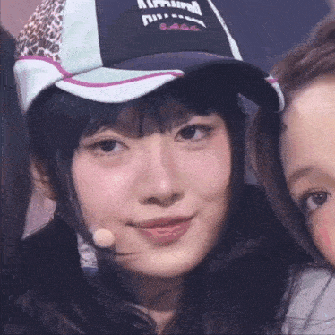 a girl wearing a hat that says ' allround ' on it stands next to another girl