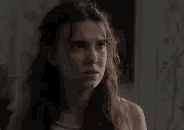 a close up of a woman 's face in a dark room with a serious look on her face .