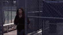 a woman is screaming in front of a chain link fence and the words fuuuuck are written in white letters .