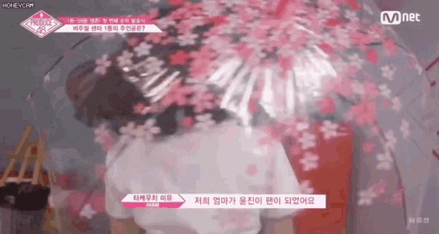 a woman in a white shirt is standing in front of a cherry blossom wall .