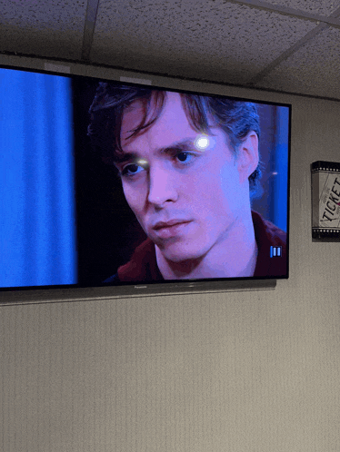 a man 's face is displayed on a television screen next to a ticket