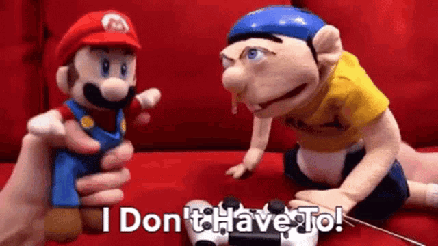 a mario and a spongebob puppet are sitting on a red couch playing a video game .
