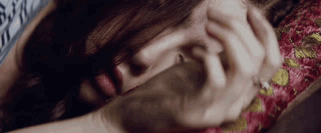 a close up of a woman 's face with a ring on her finger