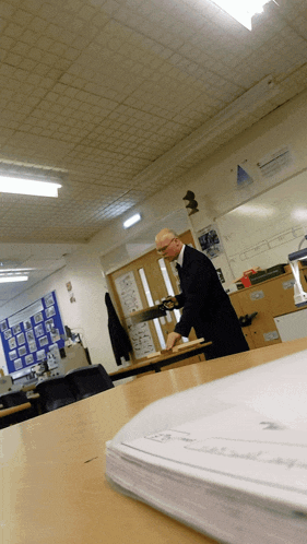 a man sits at a desk in a classroom with a sign on the wall that says " mathematics "