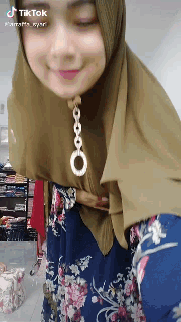 a tiktok video of a woman wearing a floral dress and a hijab