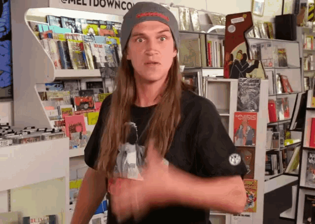 a man wearing a beanie and a black shirt stands in front of a sign that says meltdownco