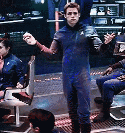 a man in a star trek uniform stands in front of a group of people sitting in chairs