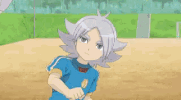 a boy in a blue shirt is kicking a soccer ball .