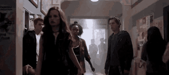 a group of people are standing in a hallway .