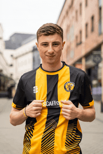 a young man wearing a black and yellow striped shirt with the word scaffolding on it