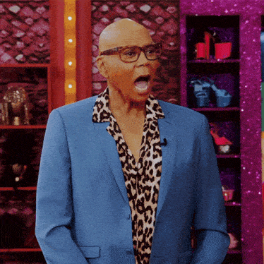 a man wearing a blue suit and leopard print shirt is making a funny face