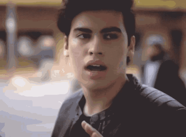 a young man with his tongue out is wearing a black jacket .