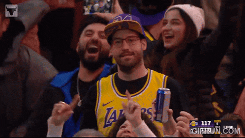 a man wearing a lakers jersey is holding a red bull can