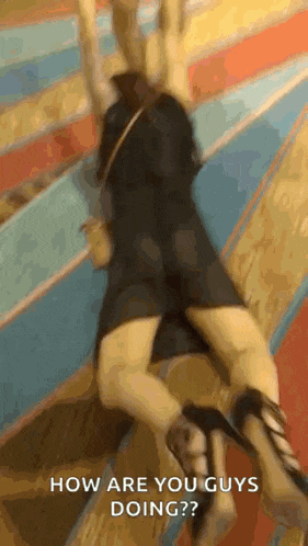 a woman in a black dress and high heels is laying on the floor and asking how are you guys doing ?
