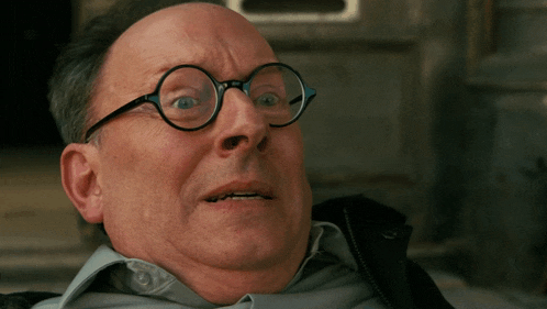 a bald man wearing glasses looks surprised and shocked