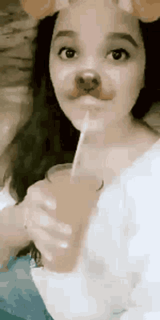 a girl is drinking a drink through a straw while wearing a dog mask .