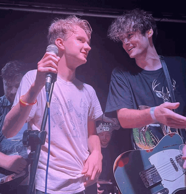 a man singing into a microphone next to a man holding a guitar