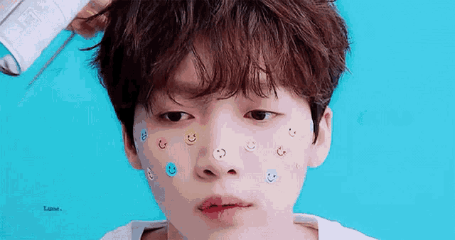 a young boy with smiley faces on his face and a blue background .