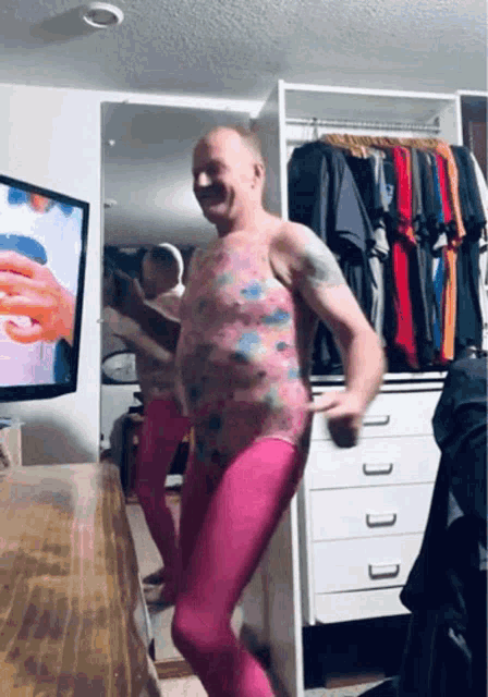 a man wearing pink tights is dancing in front of a tv