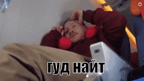 a man is laying on a bed with a phone in his ear and the words " gud nait " on the bottom right