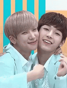 two young men are hugging each other and smiling while standing next to each other .
