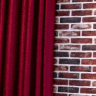 a red curtain is hanging on a brick wall next to a brick wall .