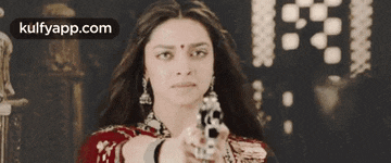a woman in a red dress is pointing a gun at the camera .