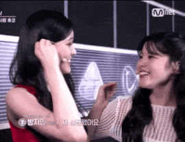 two women are touching each other 's faces and smiling while standing next to each other .