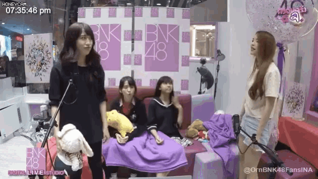a group of girls standing in front of a wall that says bnk48