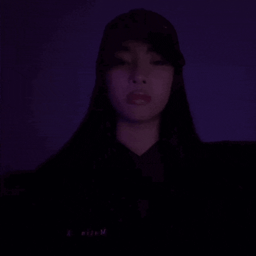 a woman is making a heart shape with her hands in the dark .