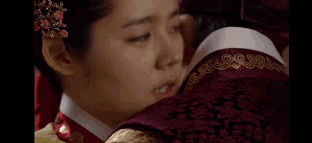 a man and a woman are kissing in a room in a traditional korean dress .