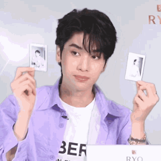a young man in a purple shirt is holding a polaroid picture