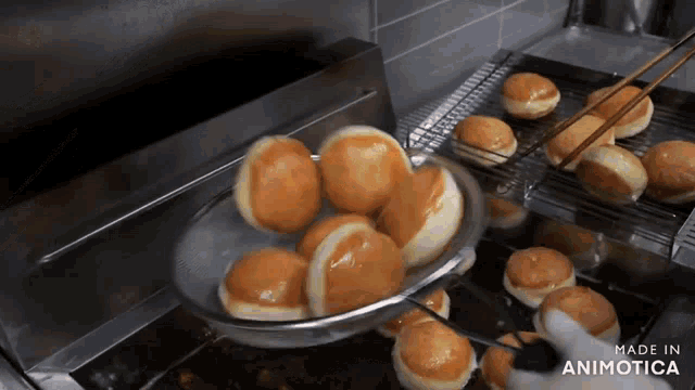 a bunch of doughnuts are being cooked in a fryer and the words made in animotica are visible