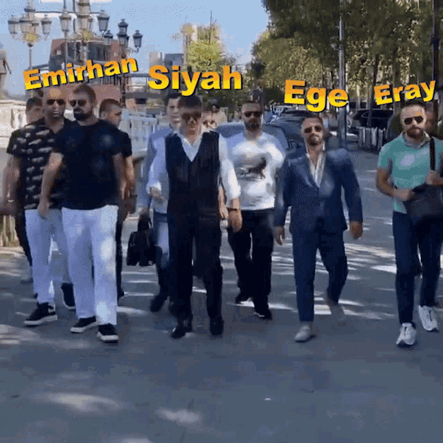 a group of men are walking down a street with the words emirhan siyah ege eray written in yellow