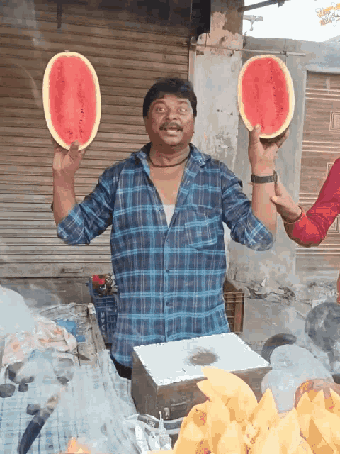 a man in a plaid shirt holds two slices of watermelon in his hands