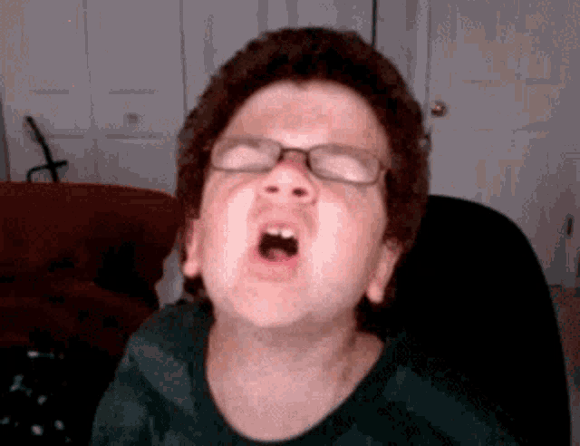 a young boy wearing glasses is making a funny face with his mouth open