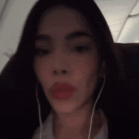 a woman is wearing headphones and making a funny face while sitting on a plane .