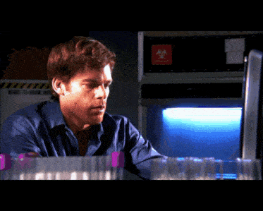 a man in a blue shirt is looking at a computer screen in front of a biohazard sign