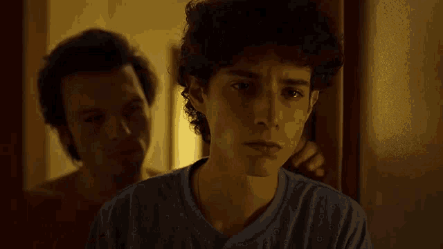 two men are standing next to each other in a dark room .