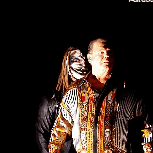 a man wearing a clown mask stands next to another man