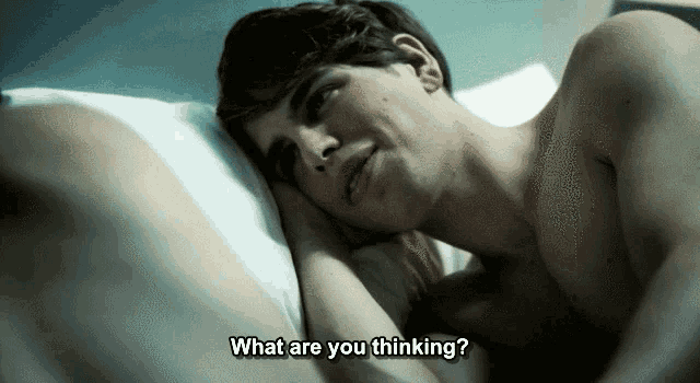 a shirtless man laying on a bed with the words what are you thinking below him