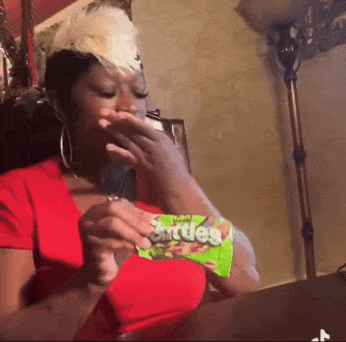 a woman is eating a bag of skittles