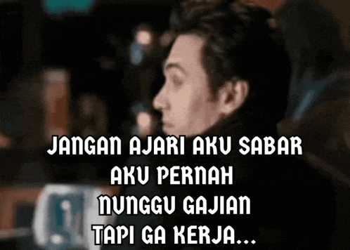 a man is sitting in front of a sign that says jangan ajari aku sabar